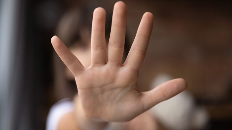 Person holding up hand blocking face from camera