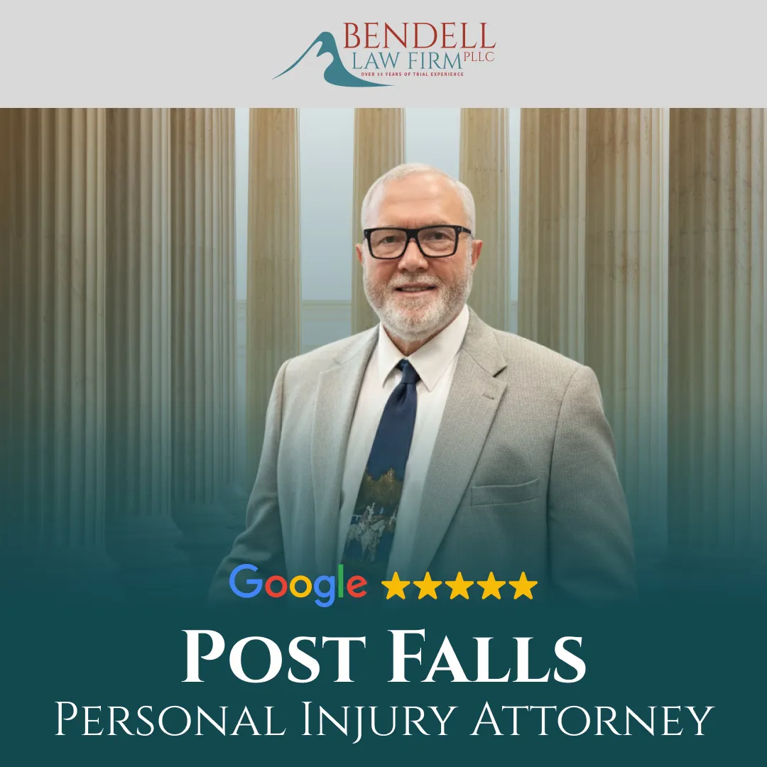 Professional portrait of a man in a light gray suit and tie with glasses, standing before classical columns, with text for Bendell Law Firm PLLC and Post Falls Personal Injury Attorney.