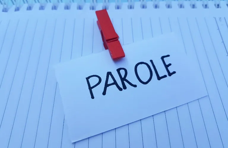White card with the word "PAROLE" clipped by a red clothespin on a lined notebook.