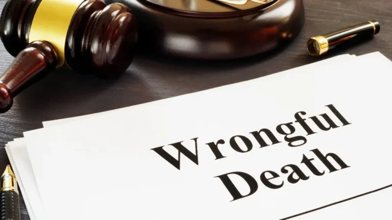 Wooden judge's gavel, pen, and documents with bold text "Wrongful Death" on dark desk.