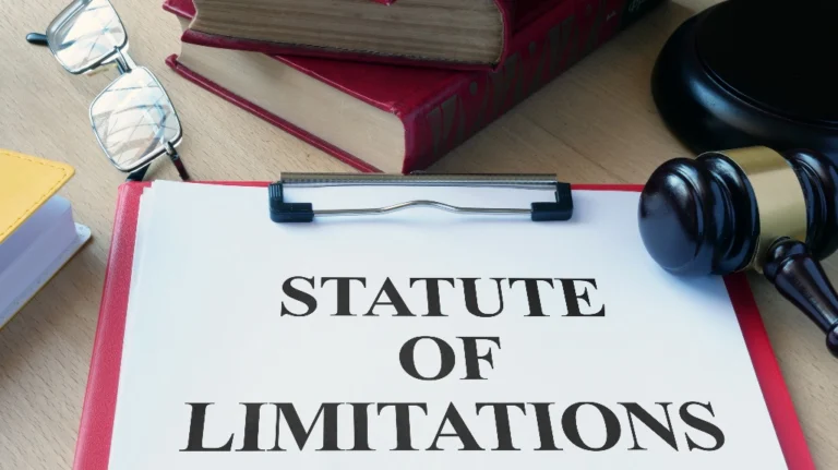 Legal document titled "Statute of Limitations" on clipboard with judge's gavel, eyeglasses, and books.