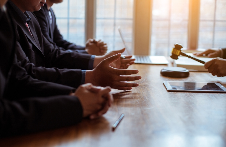 Business professionals in suits engaged in a meeting with a judge's gavel on a wooden table.