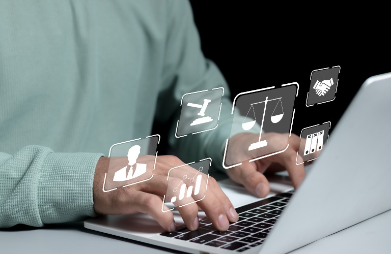 Person typing on laptop keyboard with floating legal and business icons above hands.